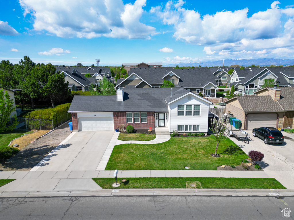 Traditional home featuring a residential view, fence, brick siding, a garage, and concrete driveway