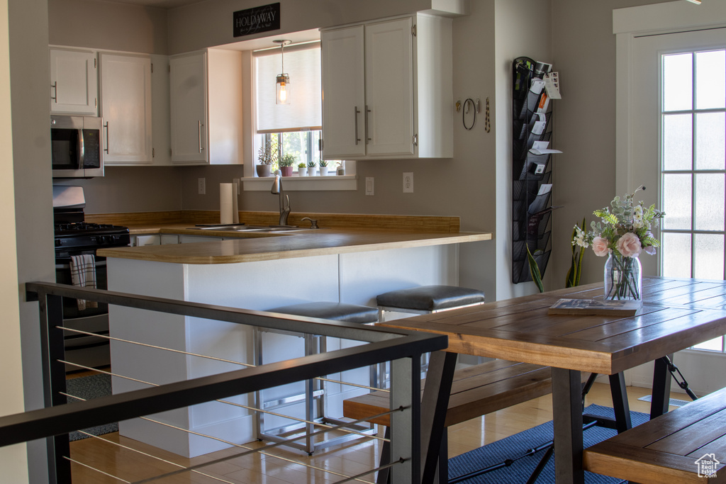 Kitchen with a sink, plenty of natural light, stainless steel microwave, and gas range