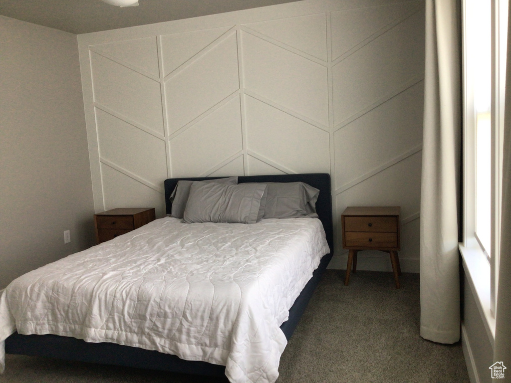 Carpeted bedroom featuring a decorative wall