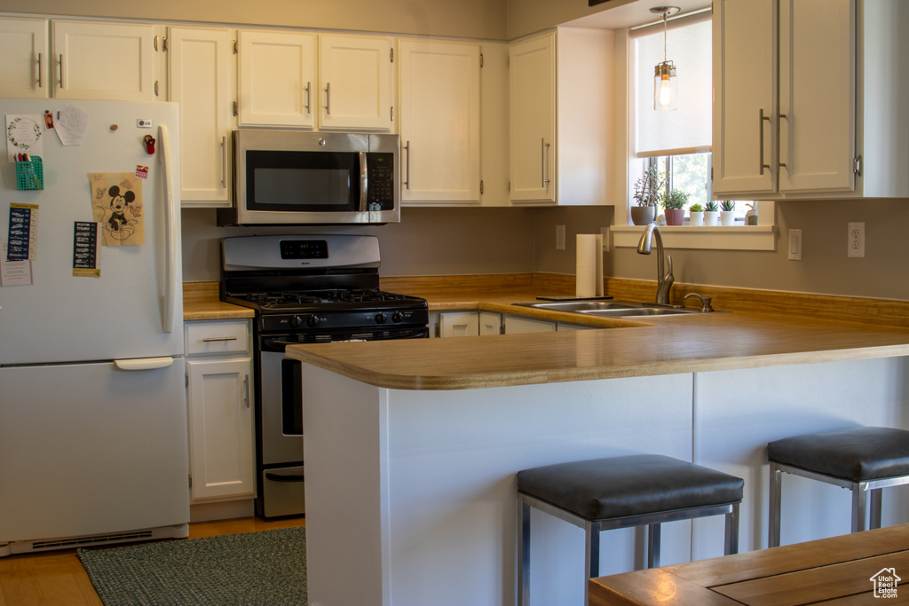 Kitchen with a sink, white cabinetry, a peninsula, and stainless steel appliances