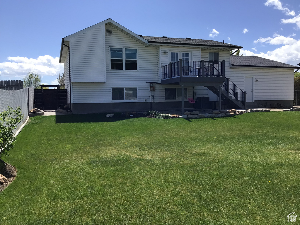 Back of house featuring a lawn, a wooden deck, stairway, and fence