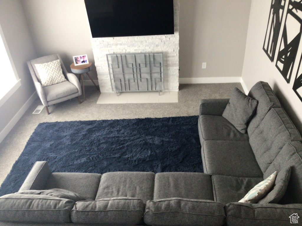 Living area with a fireplace, baseboards, and carpet