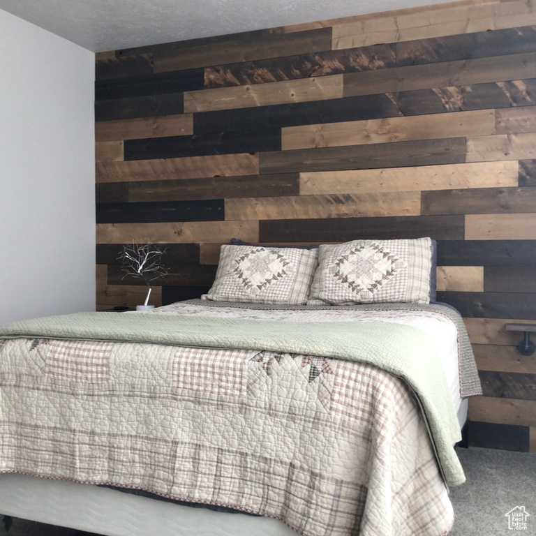 Carpeted bedroom featuring wood walls