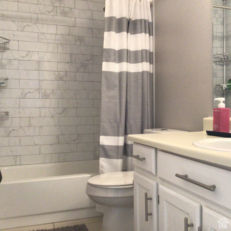 Bathroom with toilet, vanity, and shower / bathtub combination with curtain