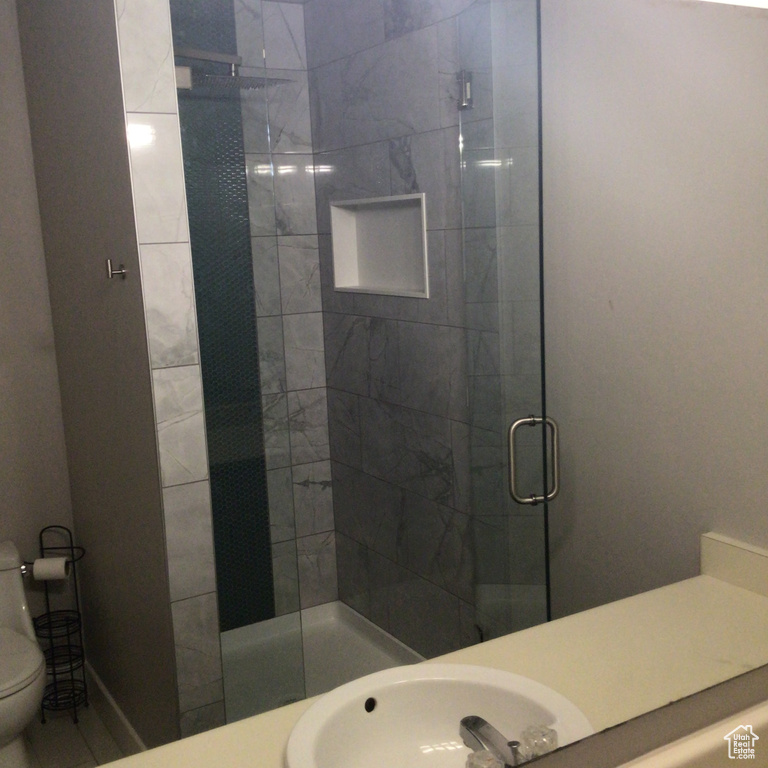 Full bathroom featuring a stall shower, a sink, and toilet