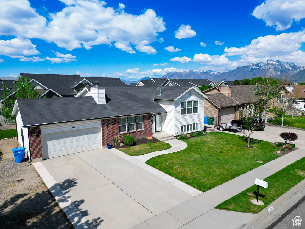 Traditional-style home with brick siding, an attached garage, a mountain view, driveway, and a residential view