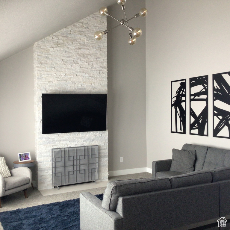 Living area featuring lofted ceiling, carpet, a fireplace, and a notable chandelier