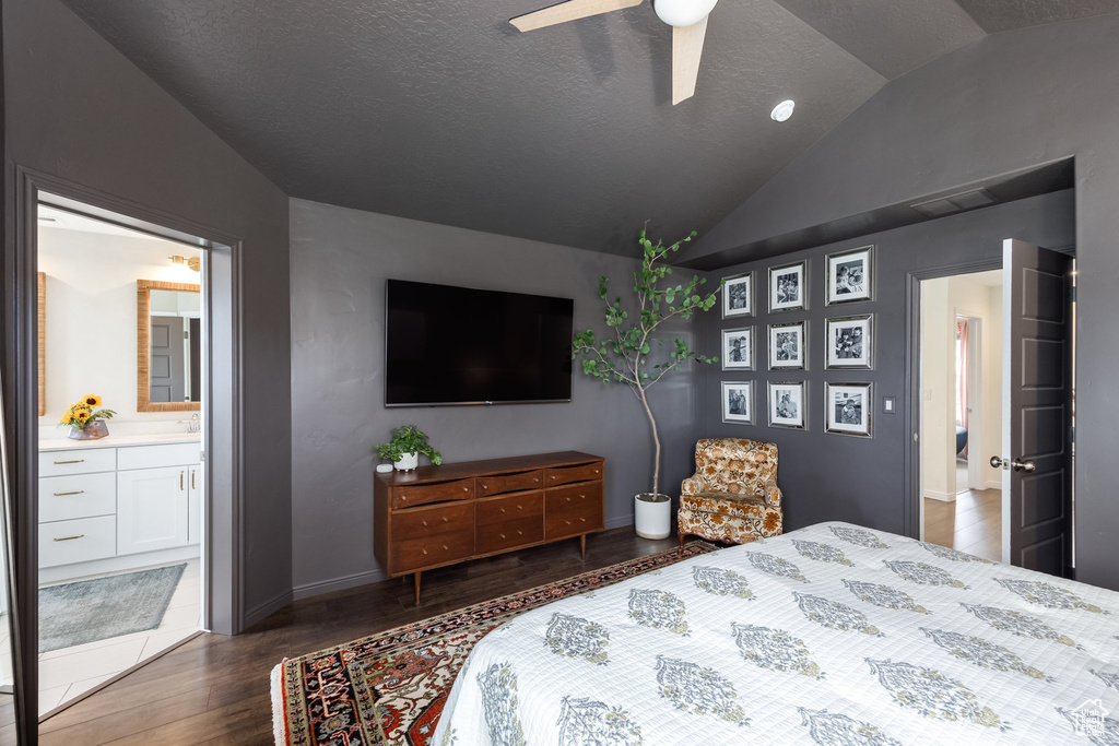 Bedroom with lofted ceiling, wood finished floors, a ceiling fan, baseboards, and ensuite bathroom