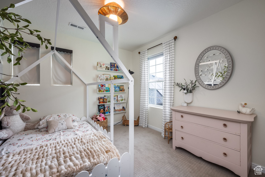 Bedroom with light carpet, visible vents, and baseboards