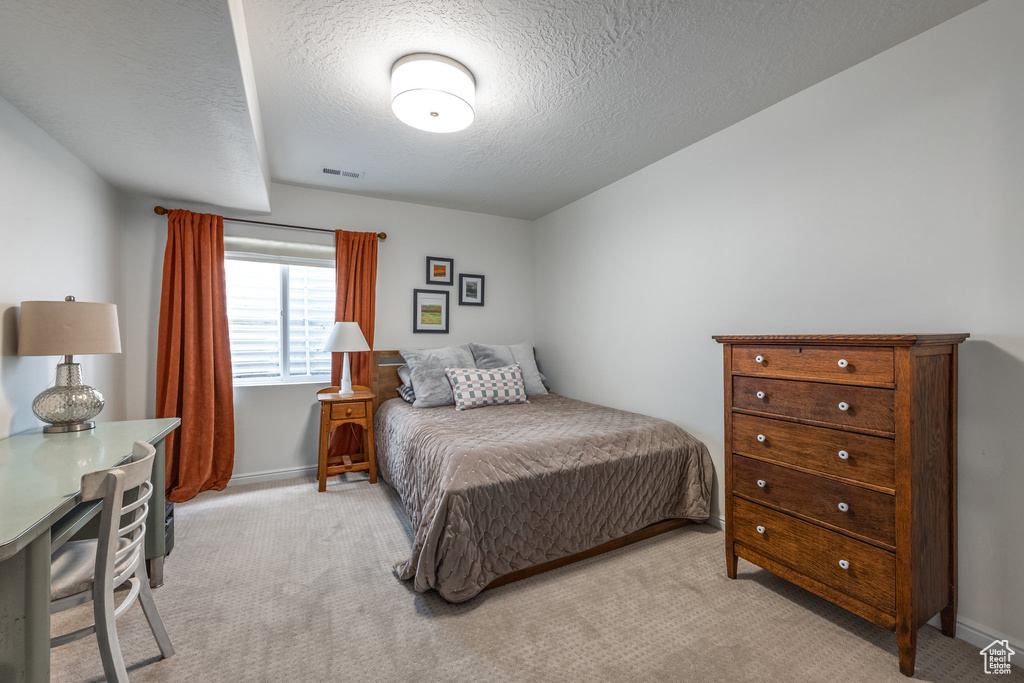 Bedroom featuring a textured ceiling, carpet, visible vents, and baseboards