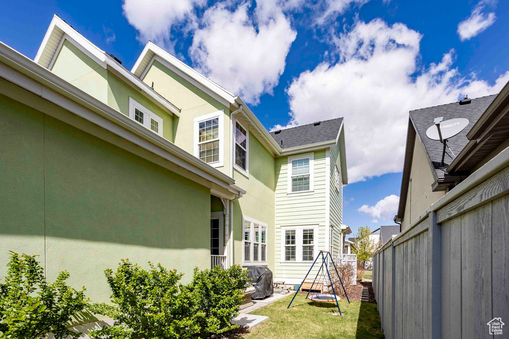 Back of property featuring fence, a lawn, and stucco siding