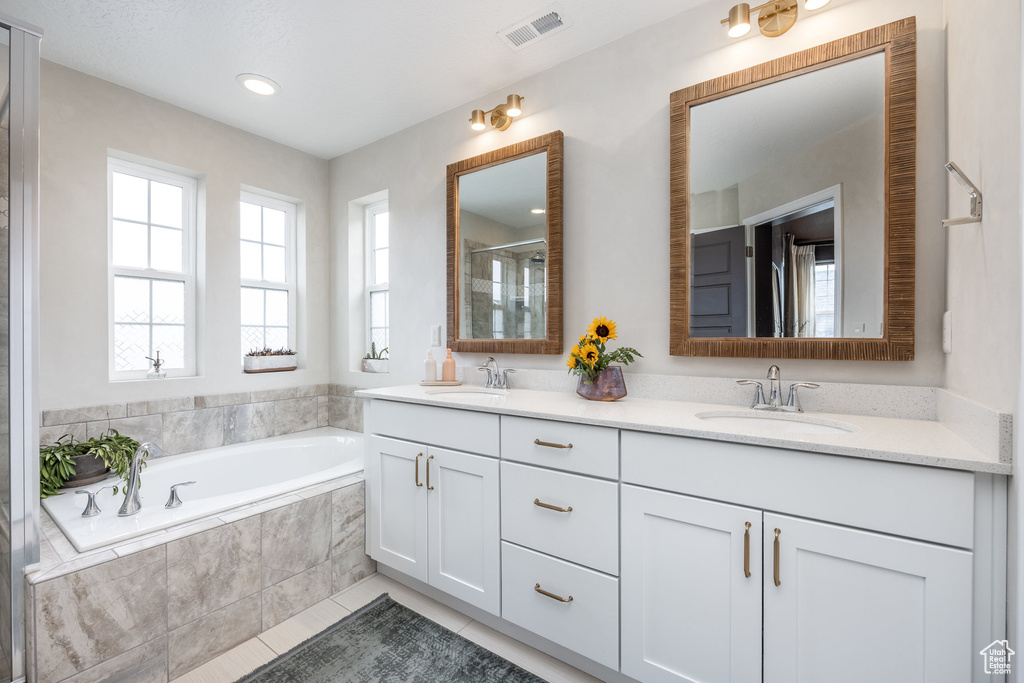 Bathroom with a bath, visible vents, a stall shower, and a sink