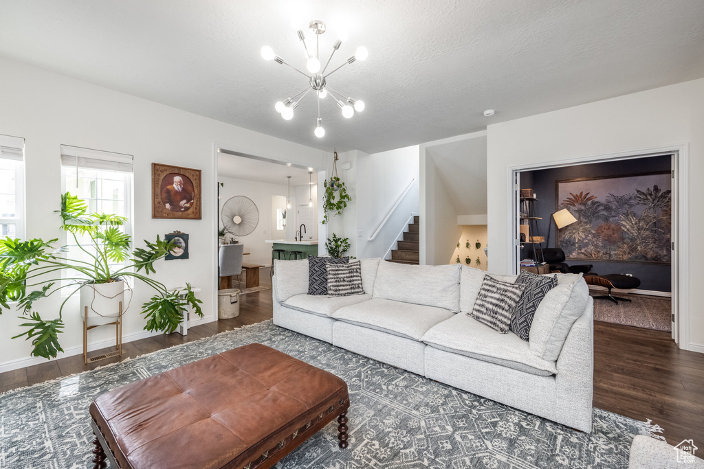 Living room with stairway, wood finished floors, baseboards, and a notable chandelier