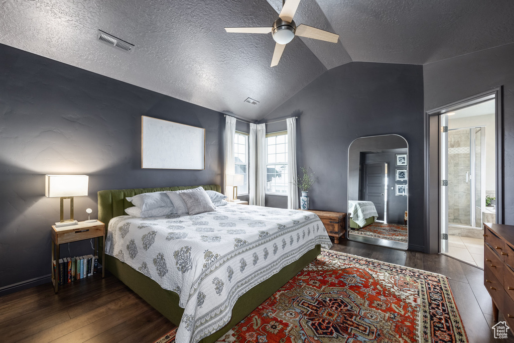 Bedroom with wood finished floors, a textured ceiling, arched walkways, lofted ceiling, and visible vents