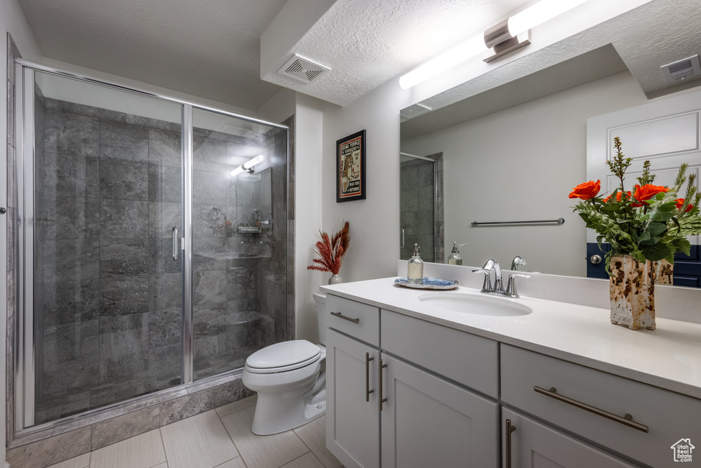 Full bath with a shower stall, visible vents, toilet, and vanity