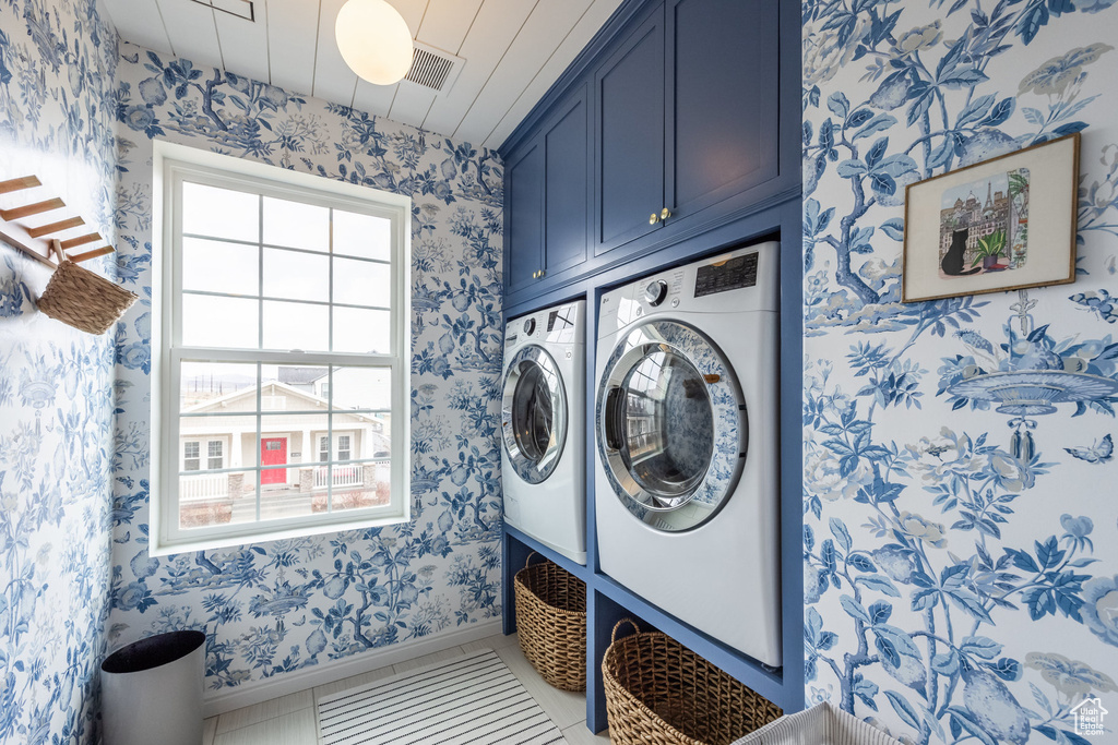 Clothes washing area with cabinet space, independent washer and dryer, and wallpapered walls