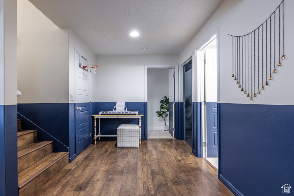 Corridor with recessed lighting, wood finished floors, baseboards, and stairway