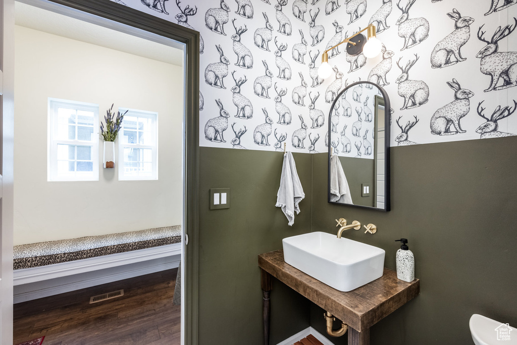 Bathroom featuring wood finished floors, visible vents, toilet, and a sink