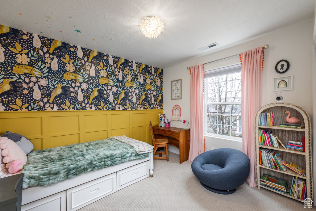 Carpeted bedroom featuring wainscoting, wallpapered walls, visible vents, and a decorative wall
