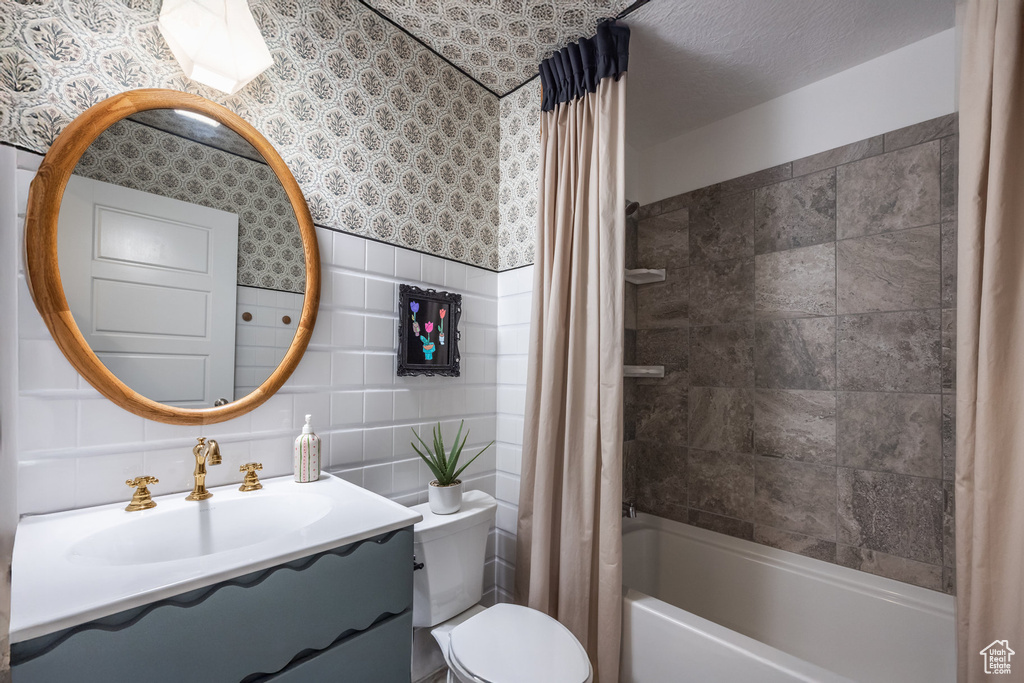Full bath with tile walls, shower / bath combo, vanity, and toilet