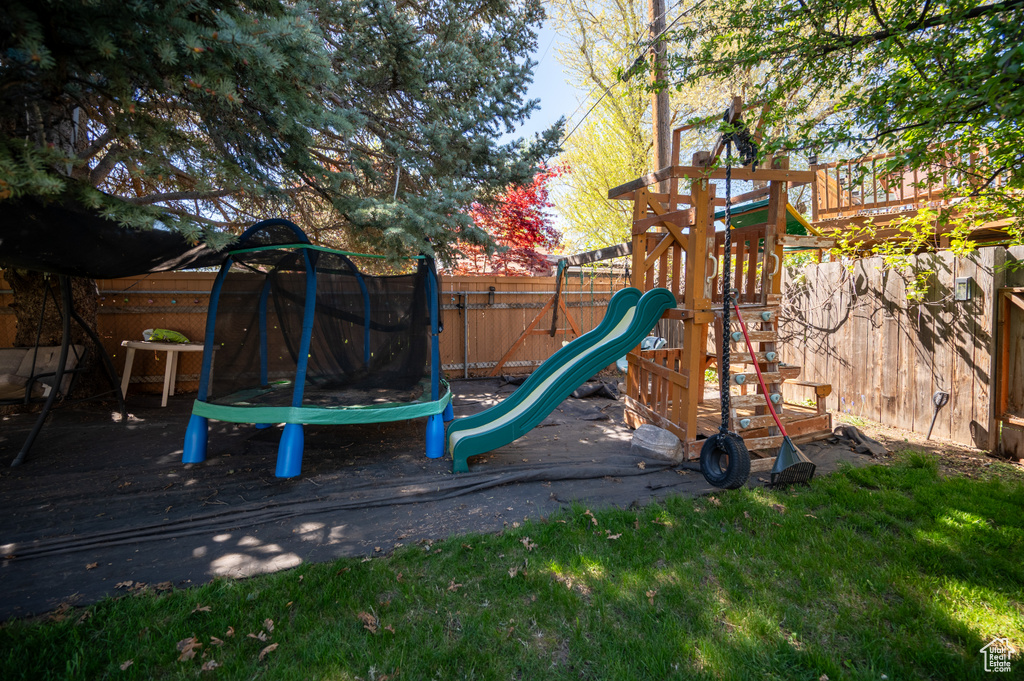 View of jungle gym with a yard, a fenced backyard, and a trampoline