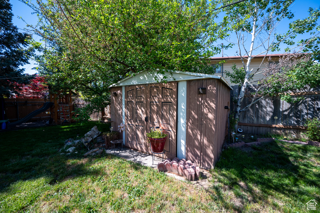 View of shed featuring a fenced backyard and a playground