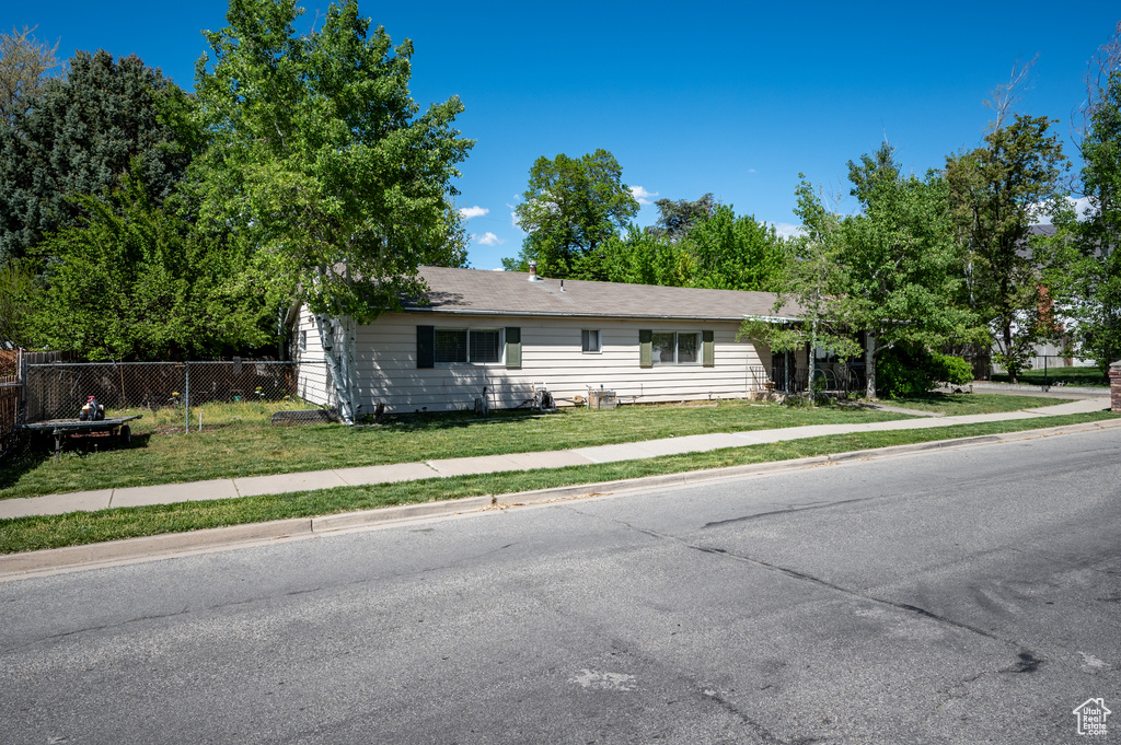 Ranch-style home featuring fence and a front lawn