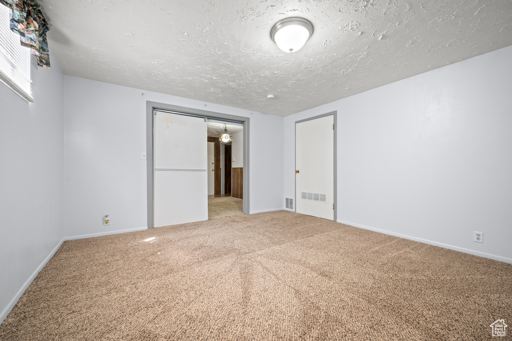 Unfurnished bedroom with carpet floors, baseboards, a textured ceiling, and visible vents