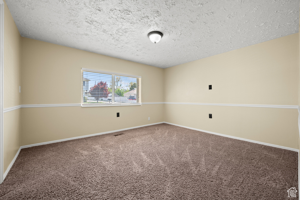 Carpeted spare room with baseboards and a textured ceiling