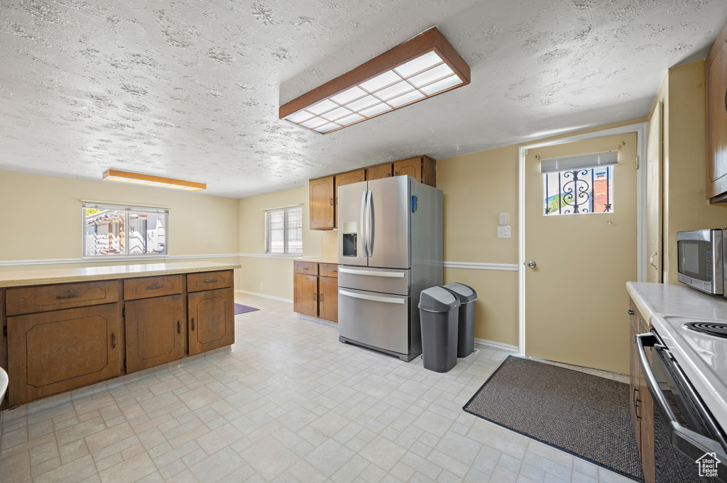 Kitchen featuring light countertops, appliances with stainless steel finishes, baseboards, and brown cabinets
