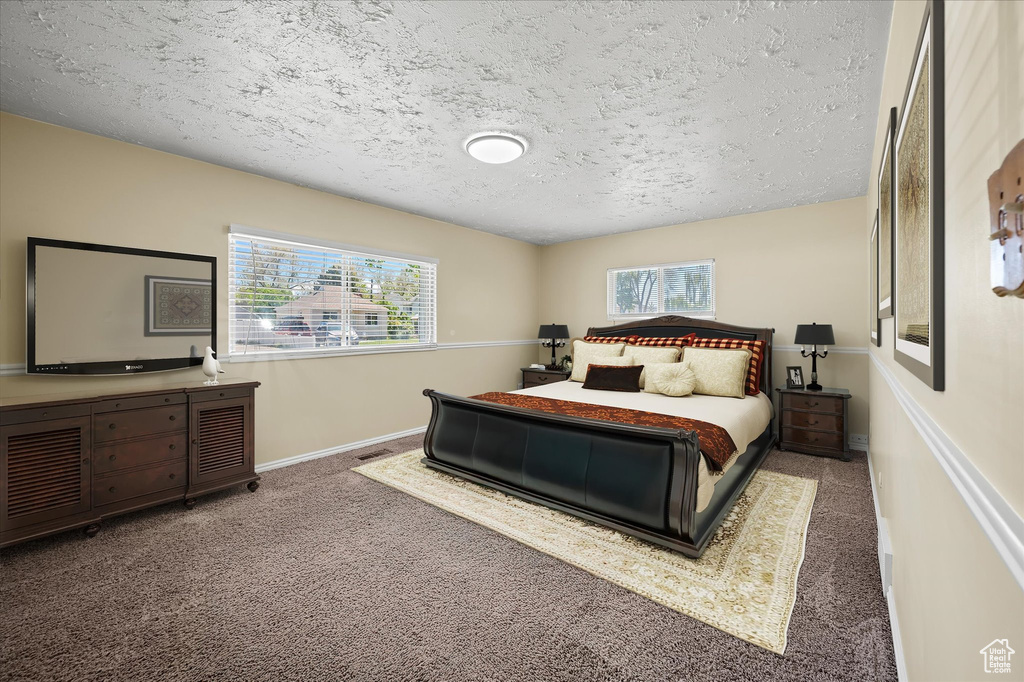 Carpeted bedroom featuring a textured ceiling and baseboards