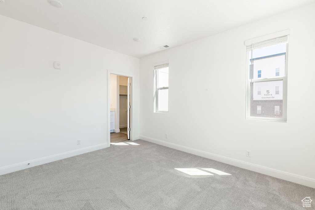 Unfurnished bedroom featuring baseboards, multiple windows, visible vents, and carpet