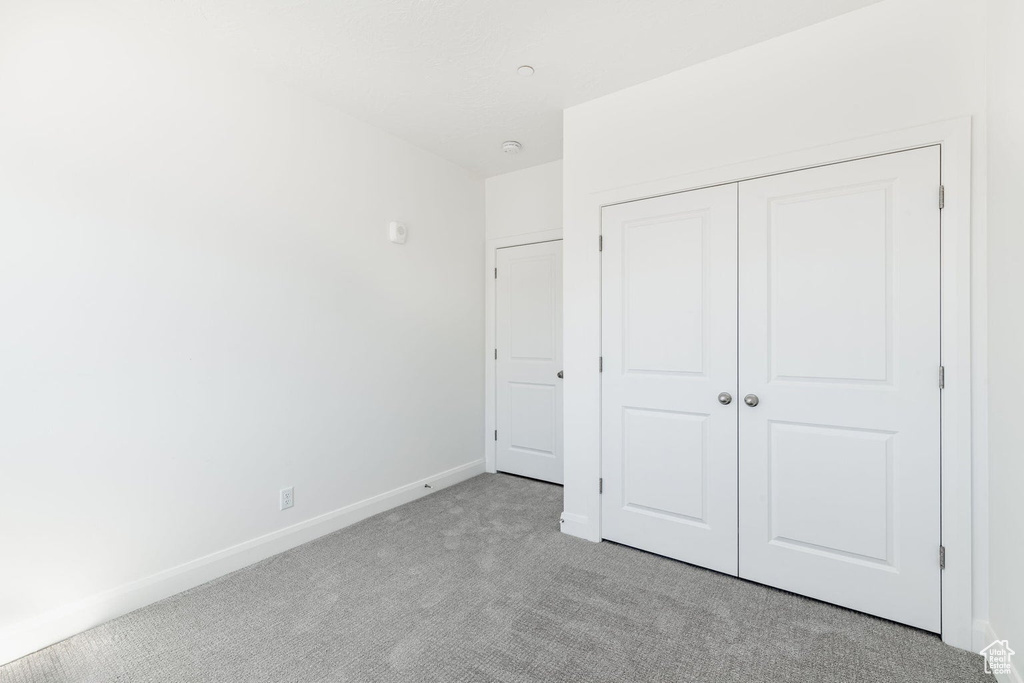 Unfurnished bedroom featuring light colored carpet, baseboards, and a closet