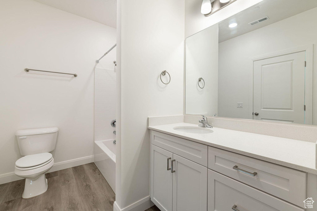 Bathroom featuring wood finished floors, visible vents, toilet, vanity, and baseboards