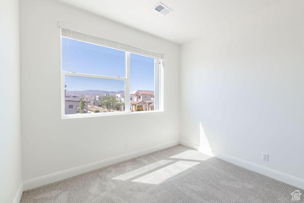 Spare room featuring carpet floors, visible vents, and baseboards