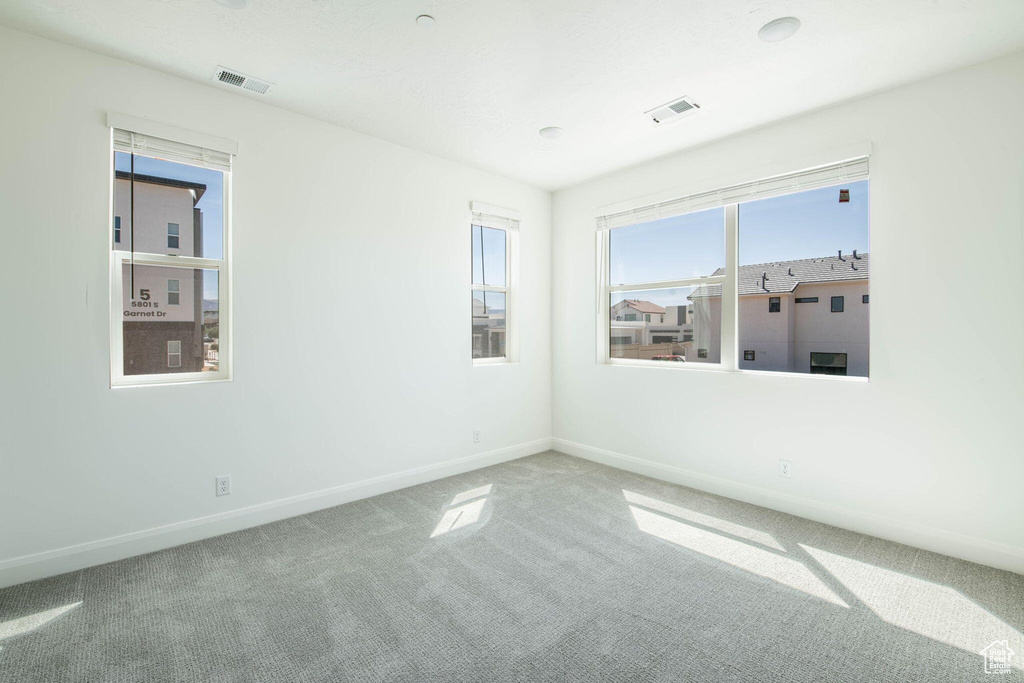 Carpeted spare room with visible vents and baseboards