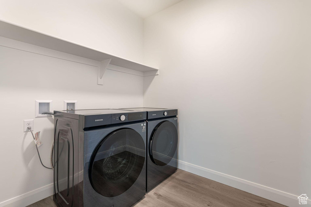 Laundry area featuring washing machine and dryer, baseboards, wood finished floors, and laundry area