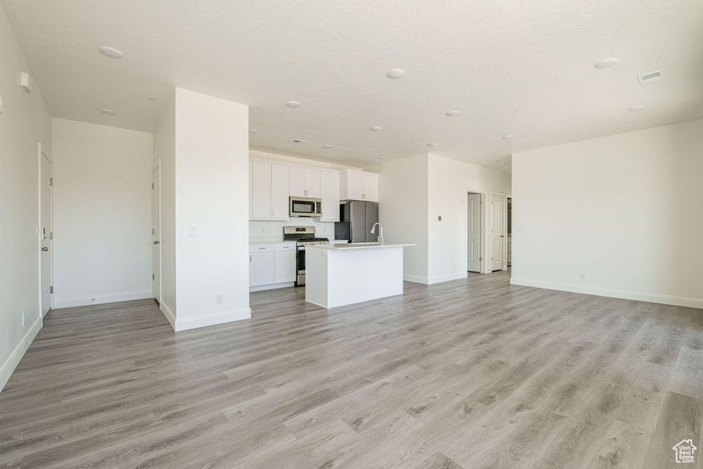 Unfurnished living room with baseboards, visible vents, and light wood finished floors