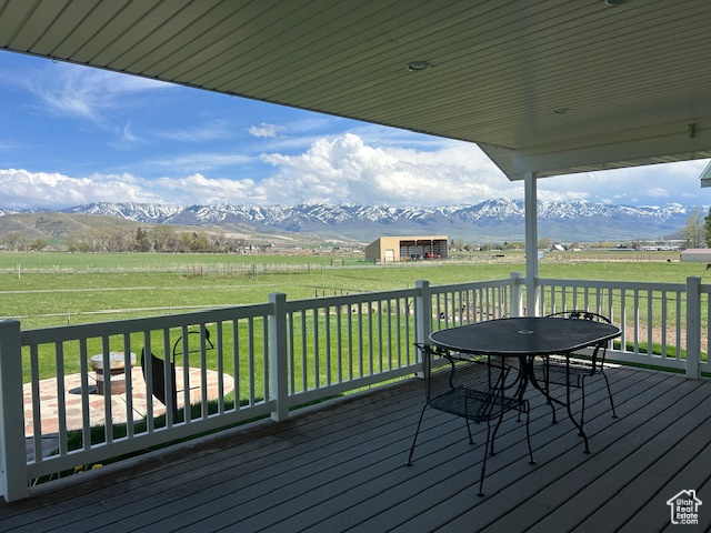 Deck with a mountain view, a rural view, outdoor dining area, and a lawn