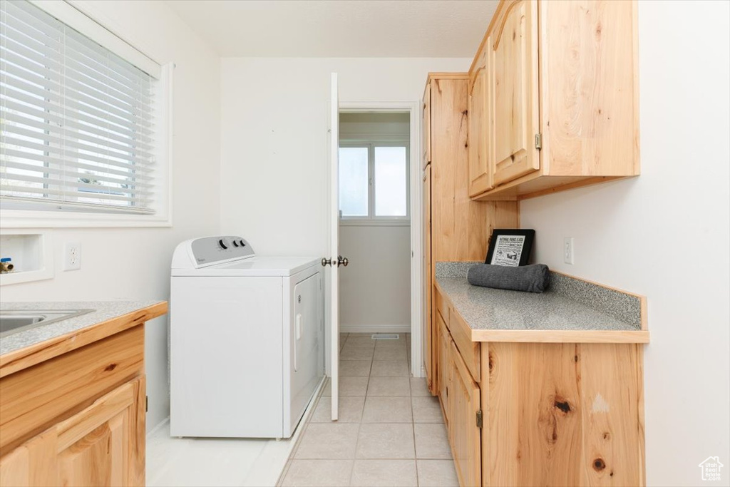 Laundry room with washer / clothes dryer, light tile patterned floors, and cabinet space