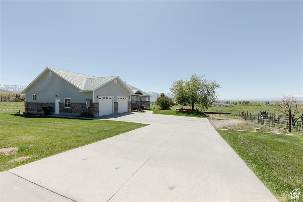 View of side of property featuring driveway, brick siding, an attached garage, and a mountain view