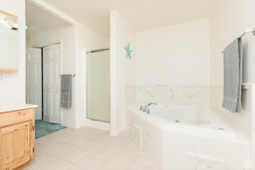 Bathroom featuring a stall shower, a tub with jets, and vanity