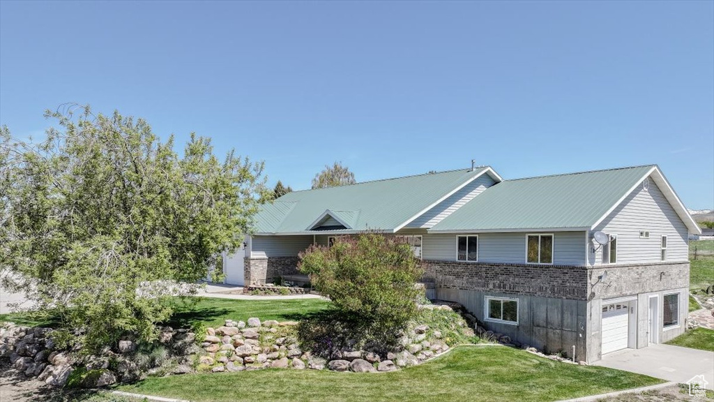 View of front of home featuring a front lawn, an attached garage, driveway, and brick siding