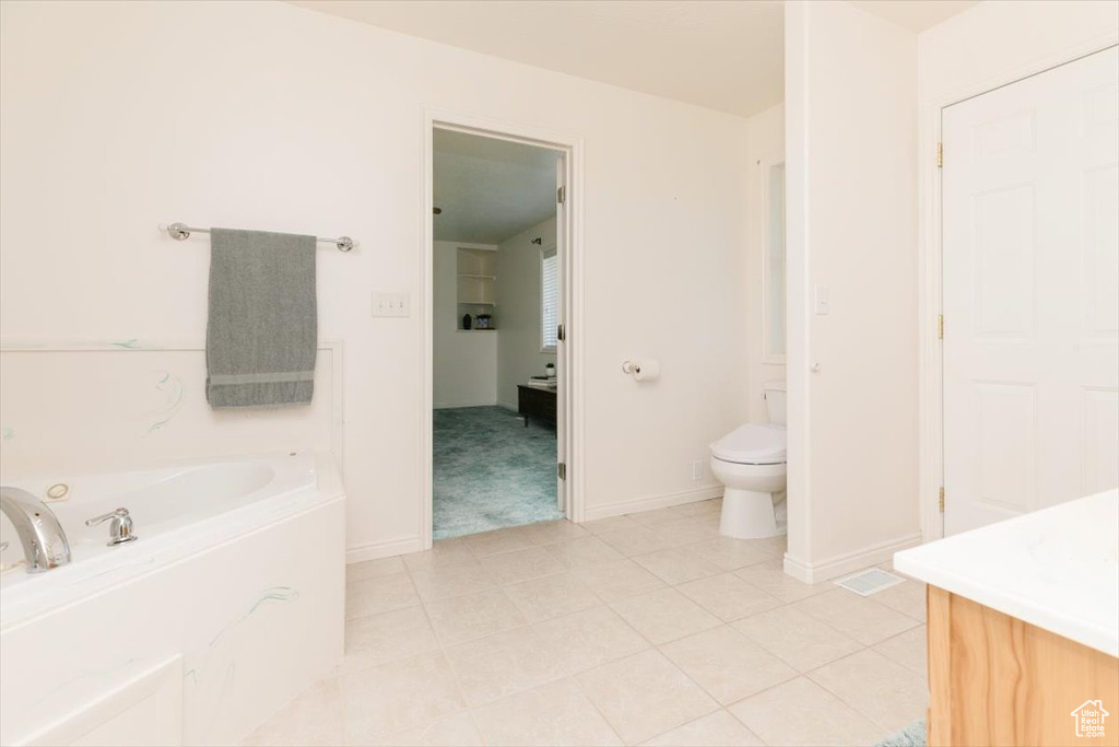 Bathroom featuring a jetted tub, vanity, and tile patterned flooring