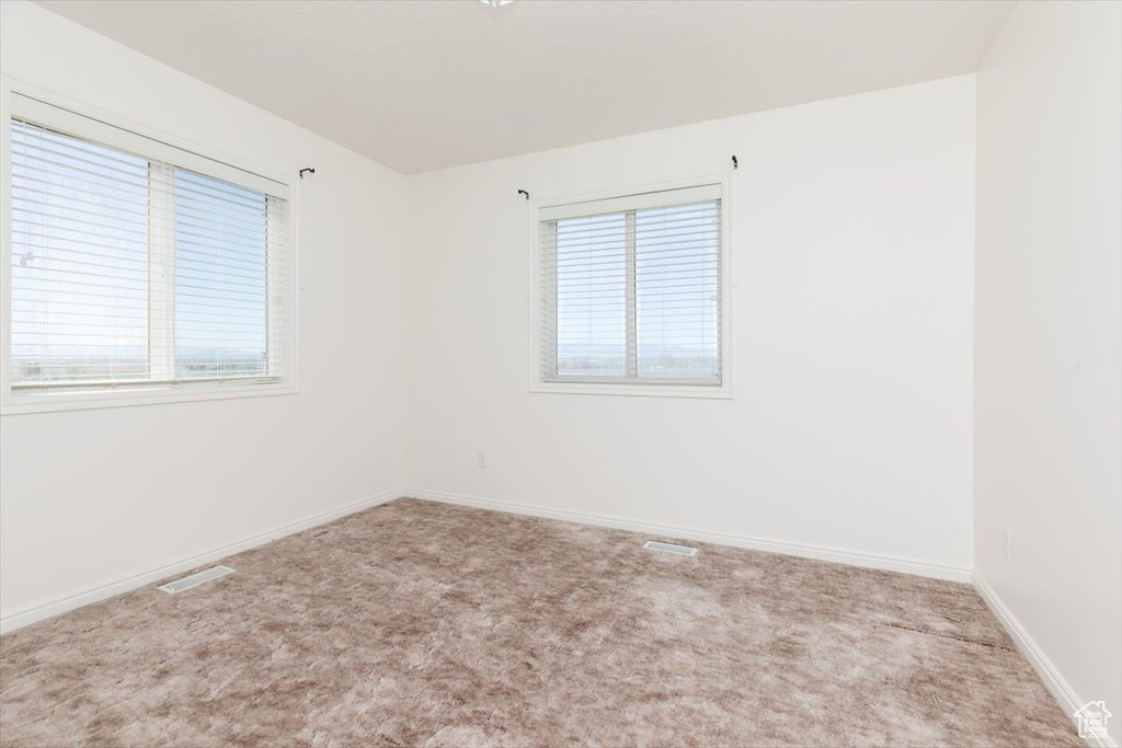Carpeted spare room featuring baseboards