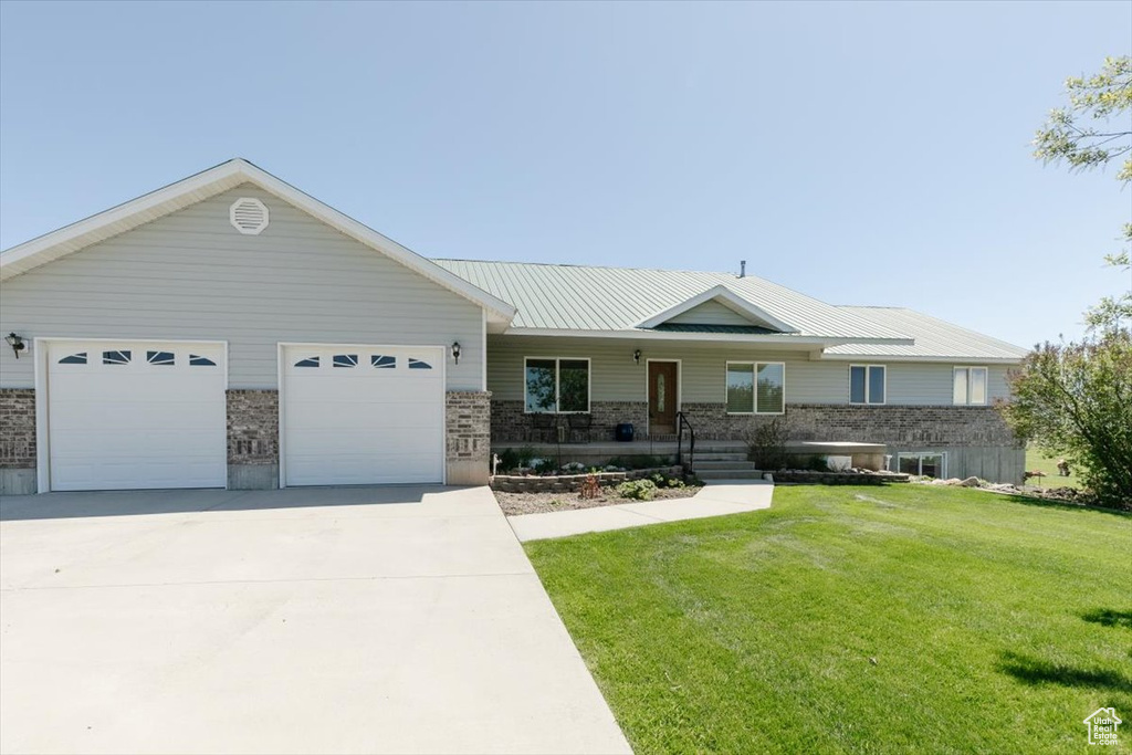 Ranch-style home featuring a front lawn, a porch, concrete driveway, an attached garage, and brick siding