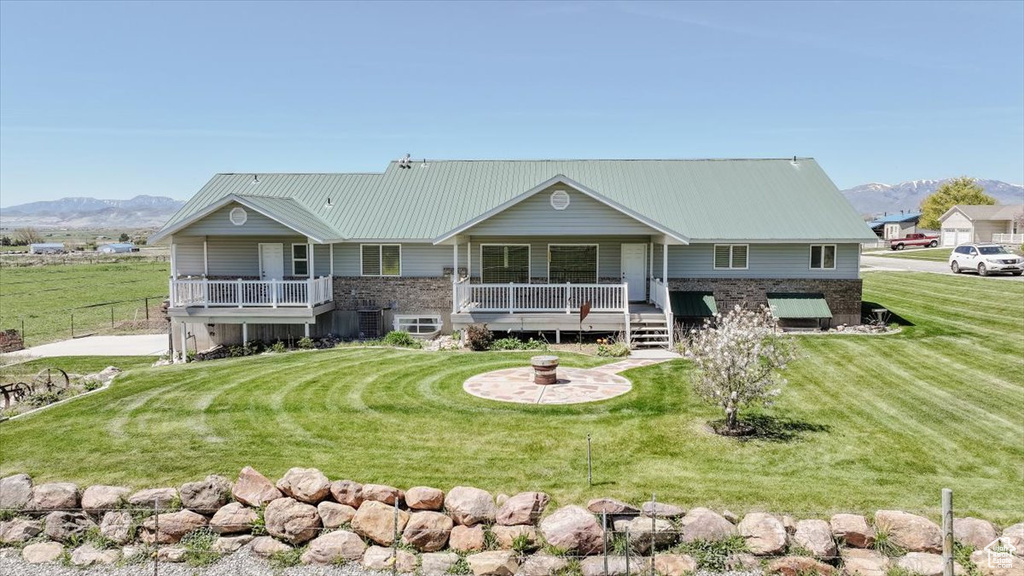 View of front facade with a mountain view, a front lawn, and a metal roof