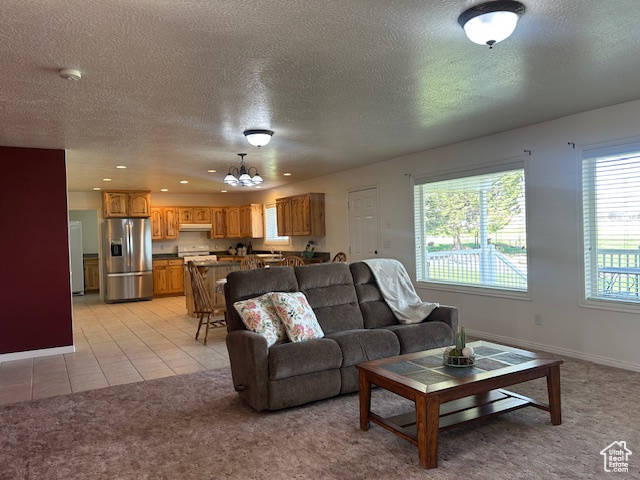 Living room with recessed lighting, an inviting chandelier, light carpet, baseboards, and a textured ceiling