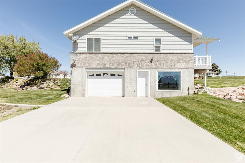 View of property exterior with an attached garage, a yard, and concrete driveway
