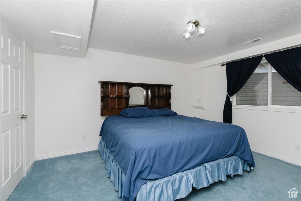 Bedroom with carpet, attic access, and a textured ceiling